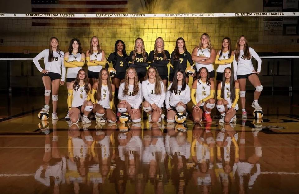 The 2026 Fairview High School varsity volleyball team posed on the court under a net banner reading Fairview Yellow Jackets.